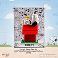 LEGO Ideas Peanuts: Snoopy's Doghouse acrylic display case (21368) shown with the assembled toy inside. The clear rectangular case features a white printed background with black comic-style drawings and the word 'SNOOPY' at the bottom.
