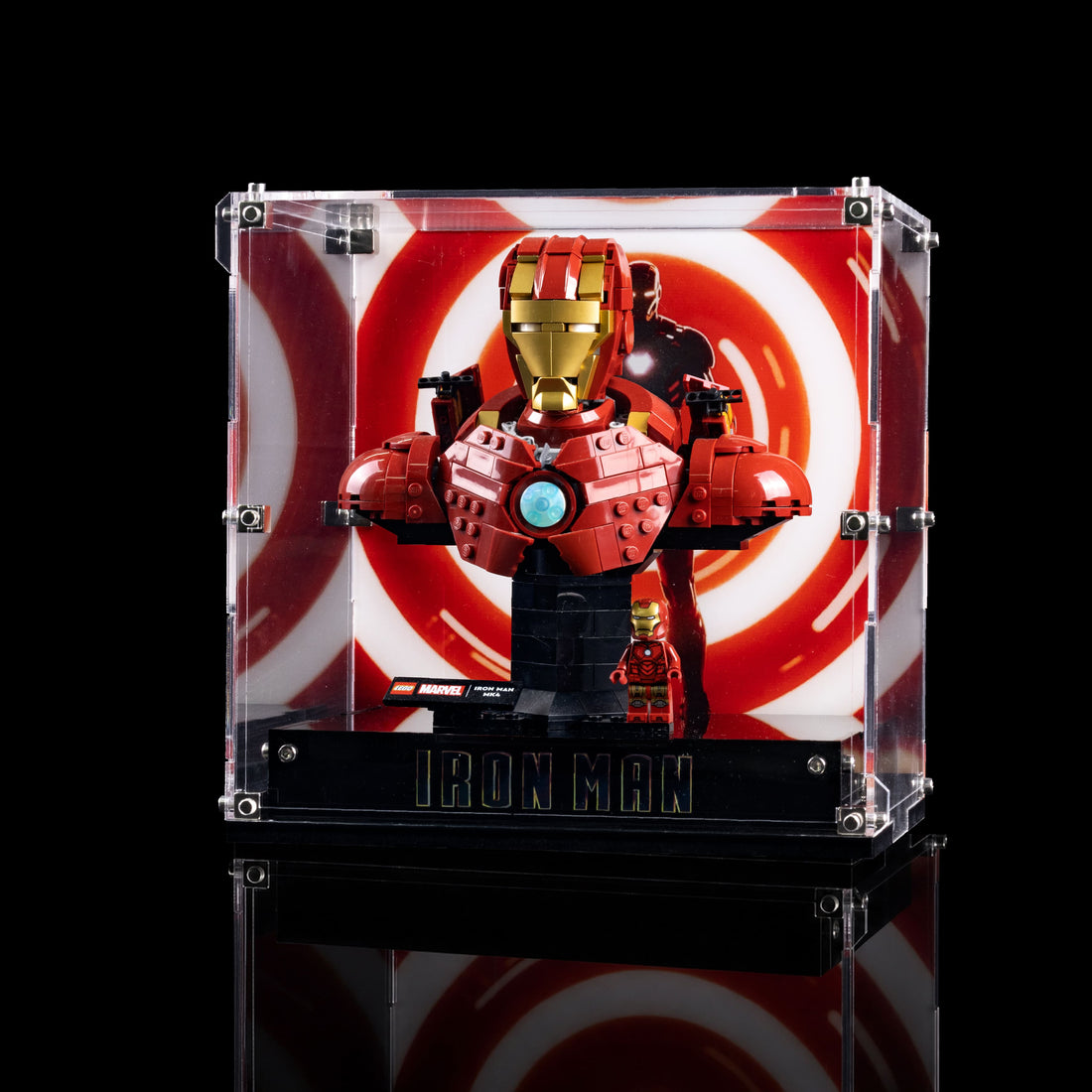 A red and gold Iron Man brick-built bust display inside a clear acrylic case with a black base labeled 'IRON MAN', shown against a black background with a red-and-white circular graphic behind it.