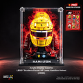 LEGO Scuderia Ferrari Lewis Hamilton acrylic display case featuring a yellow helmet and red racing suit, shown in a black studio setting with a free Hamilton sticker offer badge in the top right.