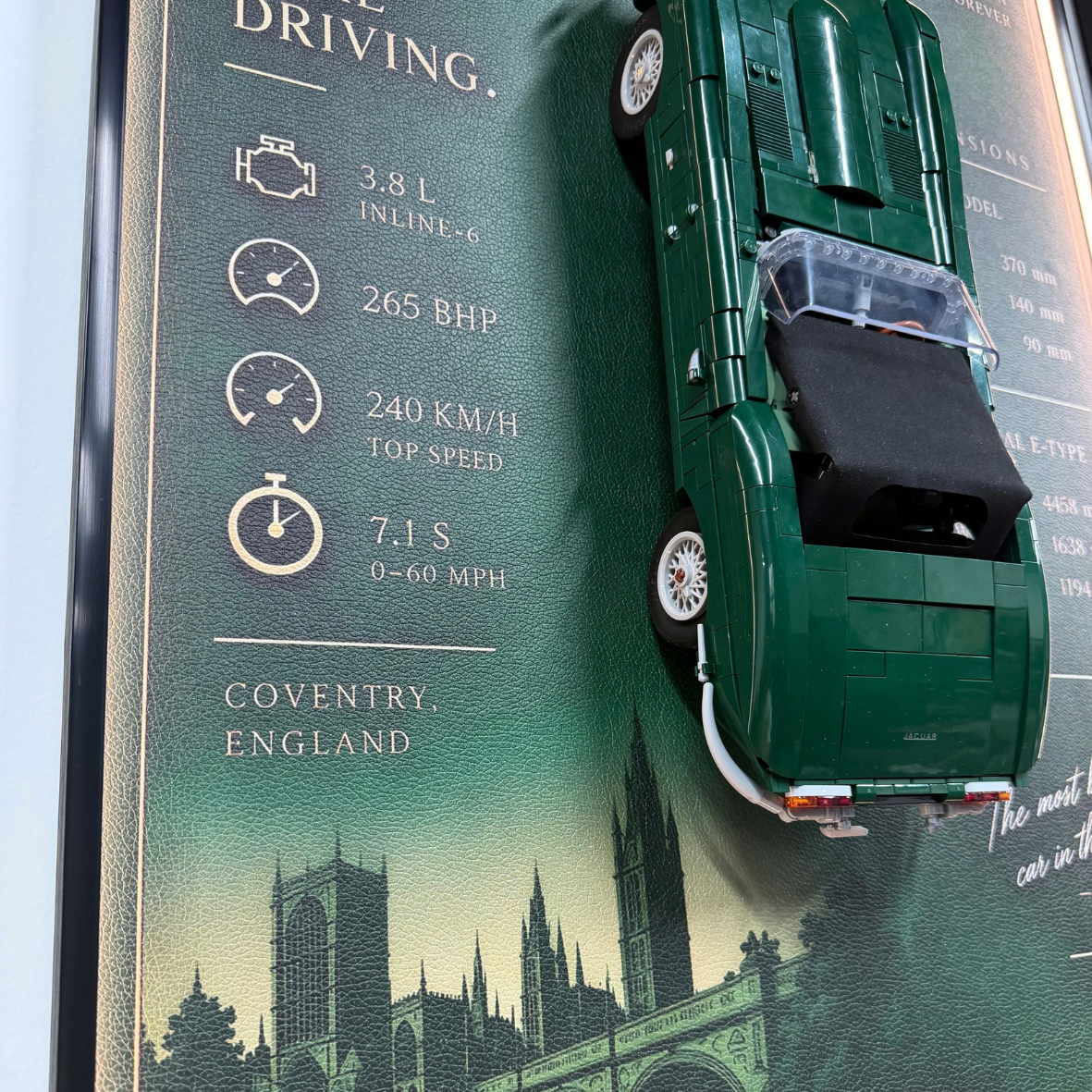 A green diecast model car displayed on a dark green informational poster featuring driving statistics and Coventry, England text with a cityscape illustration.